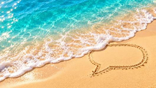 Sunny beach scene with a gentle chat-bubble wave in golden sand, representing the best time to send SMS